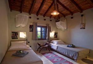 una camera da letto con due letti, una sedia e una finestra di Great Pelion Villa Villa Thalia Private Pool 3 Bedrooms Aghios Georgios a Monte Pelio