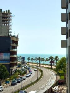 a road with cars parked on it next to the beach at Charming Batumi Apartment with City and Water Views in Batumi +2 photos