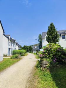 QuévenにあるAu calme - piscine, golf, merの花が咲いた2軒の白い家の間の未舗装道路
