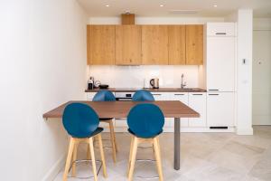 a kitchen with a wooden table and blue chairs at One Bedroom Sea View Apartment - Lustica Marina in Radovici