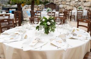 ein Tisch mit weißen Tischdecken und einer Vase mit Blumen in der Unterkunft BELMONTE RANCH in Belmonte Castello + 23 Fotos