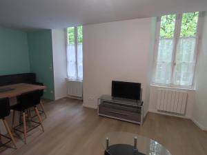 una sala de estar vacía con TV y mesa en Appartement de ville, en Parthenay