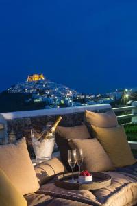 a balcony with a couch and two glasses of wine at Elegant Astypalaia Villa Villa Bianca 2 Bedrooms Hot Tub & Beautiful Sea in Astypalaia Town