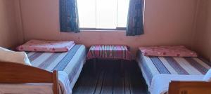 three beds in a room with a window and a window at Casa de Alejandra llachon in Llachon
