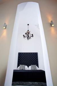 Cette chambre comprend un lit noir et un lustre. dans l'établissement Venetian-Style Santorini Villa 1 Bedroom Villa Astroglia Beautiful Caldera Sea Views & Private Jacuzzi Fira, à Fira 15 autres photos