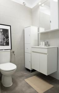 a white bathroom with a toilet and a sink at Galleria Studio in Braşov