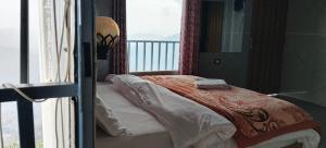 a bedroom with a bed and a window with a view at Hotel Neilkanth in Dhanaulti