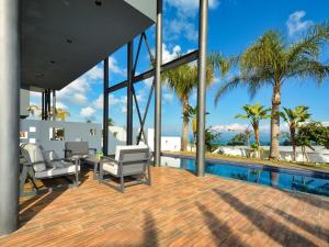un patio con sedie e una piscina con palme di Villa Limni Dyo - Luxurious Contemporary 3 Bedroom Villa With Sea Views And Hot Tub a Paralimni
