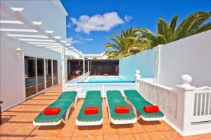 balkon z zielonymi i czerwonymi, wyściełanymi leżakami w obiekcie Great Costa Teguise Home Villa Luz De La Fragata 4 Bedrooms Private Pool Central Location w Costa Teguise