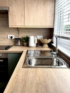 a kitchen with a stainless steel sink and wooden cabinets at Almondvale Apartment in Livingston