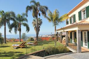 a house with palm trees in the yard at Magnificent Funchal Villa Villa Luzia 5 Bedrooms Sea & City Views in Funchal