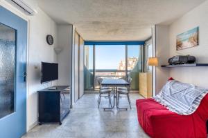 une pièce avec un canapé rouge et une table avec une télévision dans l'établissement Sur les hauteurs du Fidji, à La Grande Motte