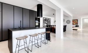 eine Küche mit schwarzen Schränken und Barhockern in der Unterkunft Dazzling Mykonos Villa Villa Lvellie 6 Bedrooms Unique Aegean Sea Views in Psarrou