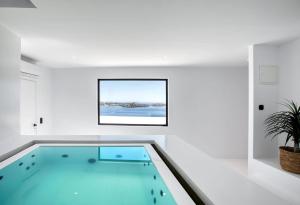 ein Swimmingpool inmitten eines weißen Raumes in der Unterkunft Dazzling Mykonos Villa Villa Lvellie 6 Bedrooms Unique Aegean Sea Views in Psarrou