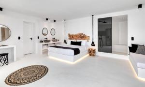 ein weißes Schlafzimmer mit einem Bett und einem Badezimmer in der Unterkunft Dazzling Mykonos Villa Villa Lvellie 6 Bedrooms Unique Aegean Sea Views in Psarrou