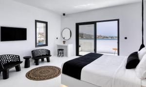 ein weißes Schlafzimmer mit einem großen Bett und einem großen Fenster in der Unterkunft Dazzling Mykonos Villa Villa Lvellie 6 Bedrooms Unique Aegean Sea Views in Psarrou