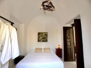 una camera da letto con un letto bianco e un lampadario di Super Luxury Santorini Villa Mansion Kyani Private Pool 3 Bdr Megalochori a Megalochori