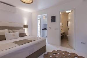 a white bedroom with a large bed and a bathroom at Executive Paros Villa Villa Aiolos Private Pool & Jacuzzi Villa Kostos Damouli in Kampos Paros +23 photos