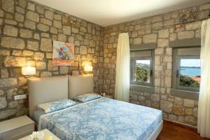 a bedroom with a bed and a stone wall at Executive Rhodes Villa Villa Ellie 2 Bedroom Villa With Sea Views Pefkos in Pefki Rhodes