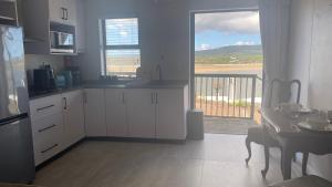 a kitchen with white cabinets and a table and a balcony at Witsand Holiday Flat in Witsand