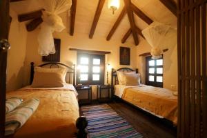 ein Schlafzimmer mit zwei Betten und zwei Fenstern in der Unterkunft Great Pelion Villa Villa Stone House 2 Bedrooms Sea View in Pilion