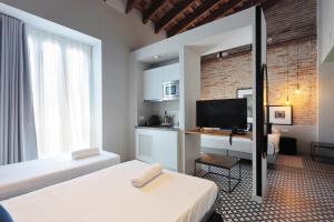 a bedroom with two beds and a desk with a television at YOU & CO. Quart Boutique in Valencia