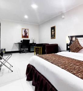 ein Hotelzimmer mit einem großen Bett und einem Schreibtisch in der Unterkunft Pasadena hotel and suites in Lagos