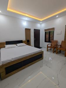 a bedroom with a large bed and two chairs at Gods Gift Homestay James Inn in Kozhikode