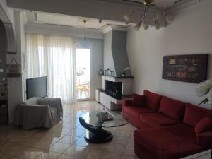 a living room with a red couch and a tv at Rafaela's Apartment in Kavála