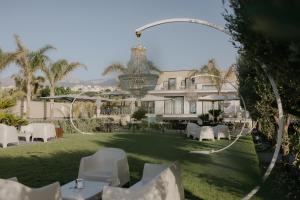 Una vista de un hotel con mesas y sillas blancas. en Palmar Boutique Hotel, en Campofelice di Roccella