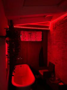 Un baño rojo con una bañera roja y una luz roja. en Oasi Del Desiderio, en Verona 13 fotos más