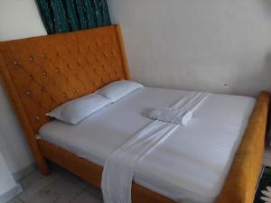 Una cama con cabecero de madera y sábanas y almohadas blancas. en Bamburi luxury studios, en Mombasa