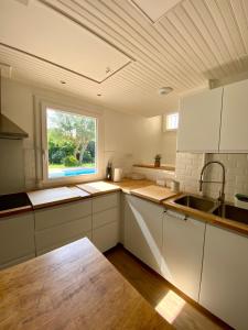 a kitchen with white cabinets and a window at Villa Labenne Ocean - piscine, 500 mètres de la plage in Labenne