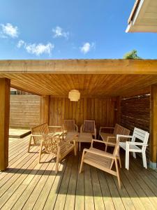 a wooden deck with tables and chairs on it at Villa Labenne Ocean - piscine, 500 mètres de la plage in Labenne +29 photos