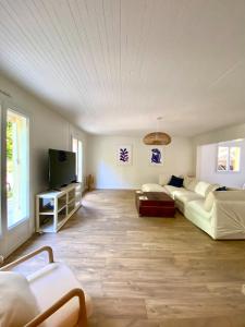 a living room with a couch and a tv at Villa Labenne Ocean - piscine, 500 mètres de la plage in Labenne