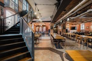 a restaurant with tables and chairs and a staircase at Craft Beer Central Hotel in Gdańsk