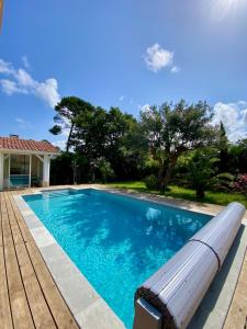 a swimming pool with a bench next to a house at Villa Labenne Ocean - piscine, 500 mètres de la plage in Labenne