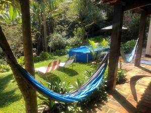 a hammock in a garden with chairs and a blue tent at Casa de Campo & Home Office - Itapecerica da Serra , perto do Embu das Artes in Itapecerica da Serra