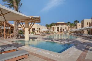 a pool at a resort with chairs and umbrellas at Steigenberger Golf Resort El Gouna in Hurghada