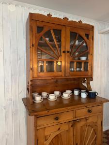 a wooden cabinet with a bunch of cups on it at Cisza pod Tatrami in Bukowina Tatrzańska +34 photos