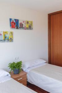 ein Schlafzimmer mit 2 Betten und einer Pflanze auf einem Tisch in der Unterkunft BaruHaus piscina y parking Rianxo x2 in Rianjo