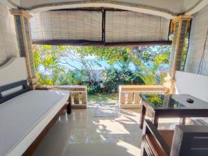 a room with a bed and a table and a window at Solaluna Beach Homestay in Amed