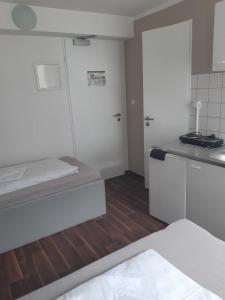 a kitchen with white cabinets and a wooden floor at 2-Rent Group Hostel Apartments SEN14 in Munich
