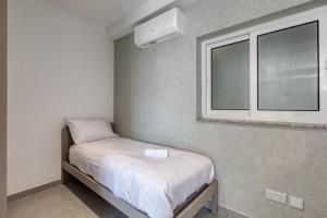 a small bed in a room with a window at Stylish Apartment Heart of St Julians Sleeps 5 in San Pawl il Bahar +26 photos
