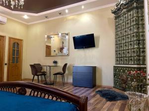Una sala de estar con una mesa y un televisor en la pared. en Apartments De-Ribas, en Odessa
