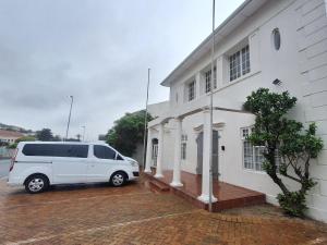 a white van parked in front of a white building at BIM Backpackers In Muizenberg in Muizenberg