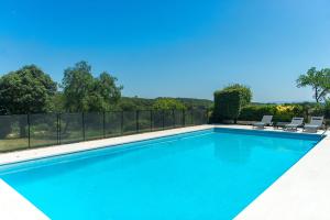 a blue swimming pool with chairs and a fence at WELCS CASA 272 PDA con piscina privada in Garrigolas