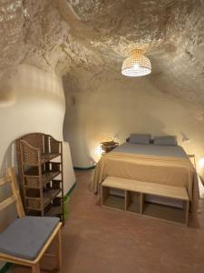 a bedroom in a cave with a bed and a chair at Bellísima cueva acogedora "Casa Olivia" in Gor