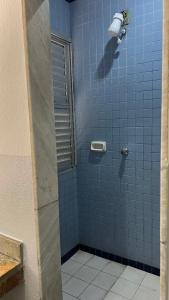 a bathroom with a blue tiled shower with a window at Hotel Angely in Belo Horizonte