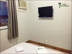 a room with a bed and a tv on the wall at Hotel Palmeiras Ltda in Duque de Caxias